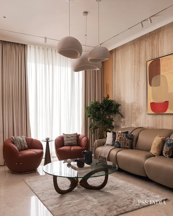 This living room is a study in balance. The soft curves of the sofa and armchairs are set against the clean lines of the travertine wall panels, creating a space that feels both modern and organic.