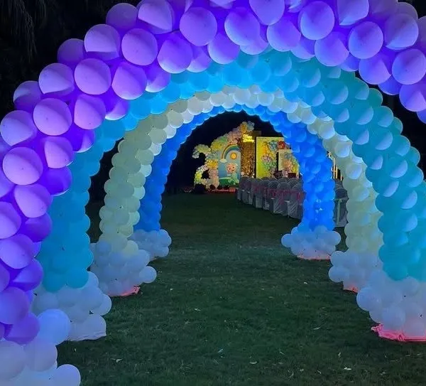 An incredible rainbow balloon tunnel entrance for a Cocomelon party, lit from within to create a magical pathway for guests.