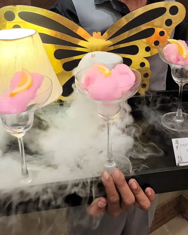 Our beautiful Candyfloss Cosmo is a visual treat. Served in a martini glass with a puff of pink candy floss, it's presented on a tray with billowing dry ice smoke.