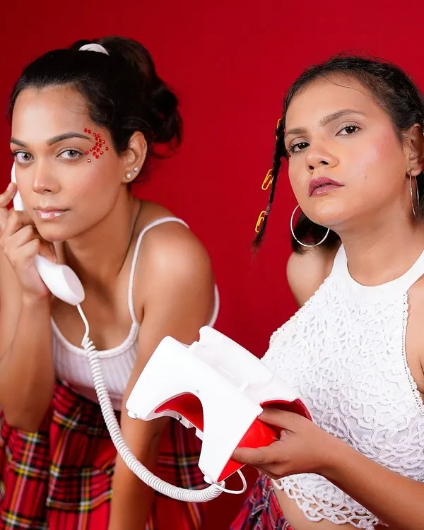 A playful and retro-inspired editorial shot. The bold red background, vintage telephone prop, and Y2K styling come together to create a fun and vibrant story with a strong narrative feel.