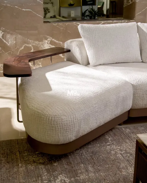 A detail of the Verona Curve Sofa, inspired by Italian mid-century modern aesthetics. The floating arm ledge, crafted from hand-finished walnut, is both a beautiful design accent and a functional surface, showcasing our approach to integrated design.