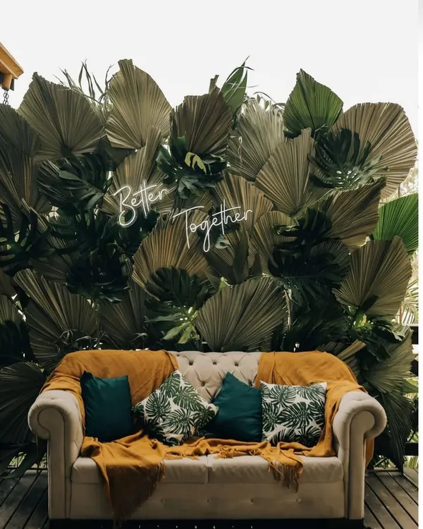 Personal touches make a wedding special. We designed this cozy seating area with a custom "Better Together" neon sign against a backdrop of tropical leaves, perfect for a modern Mehendi or pre-wedding photoshoot.