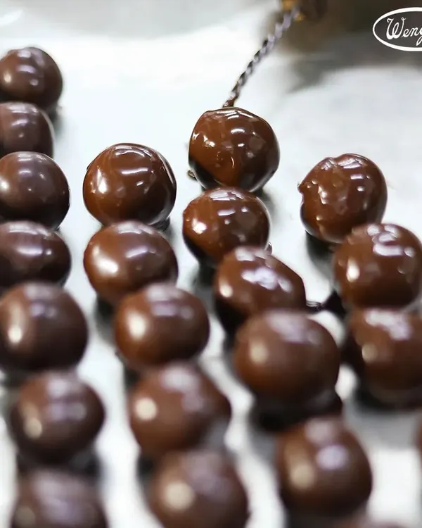 A look at our chocolate-making process. Here, our freshly made chocolate balls are being dipped one by one to create the perfect coating for our handmade truffles.