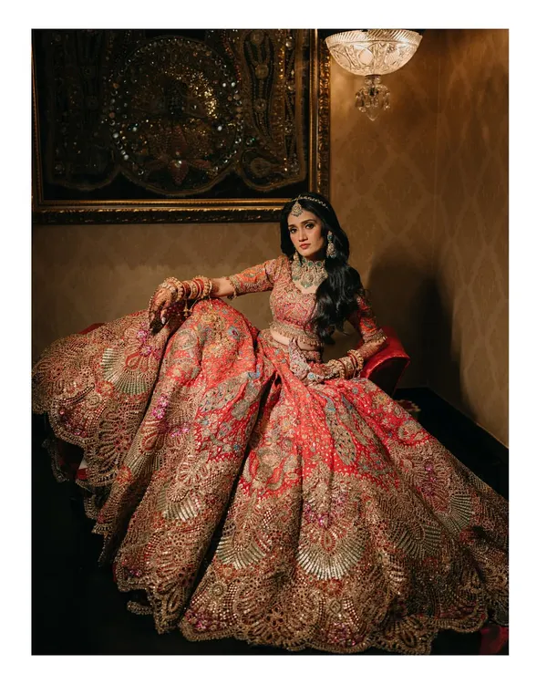 A portrait that is all about the grandeur of the bridal lehenga. The intricate embroidery and the sheer volume of the skirt create a stunning image of bridal opulence at The Leela Palace Udaipur.