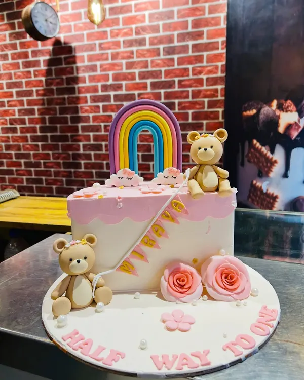 A sweet "Half way to one" cake for a 6-month celebration. This design features cute teddy bears, a colorful rainbow, and delicate pink roses.