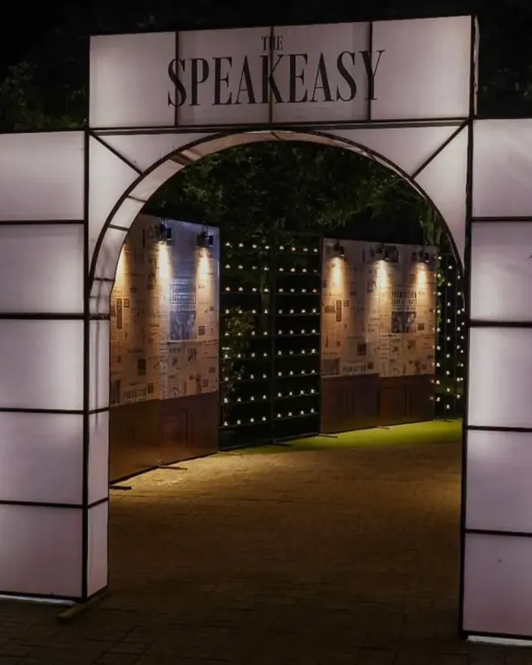The entrance to our speakeasy event, complete with a custom-built arch and walls collaged with vintage newspaper prints announcing the end of Prohibition. This set the stage for the mystery and excitement inside.