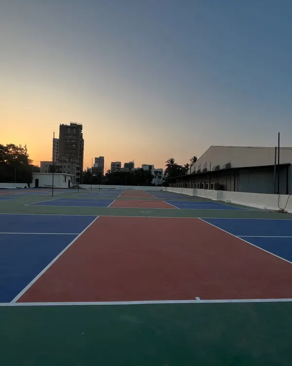 Welcome to the Maniac Pickleball Arena in Vile Parle. This is a wide view of our multiple international standard terrace courts, captured during a beautiful Mumbai sunset, ready for your next game.