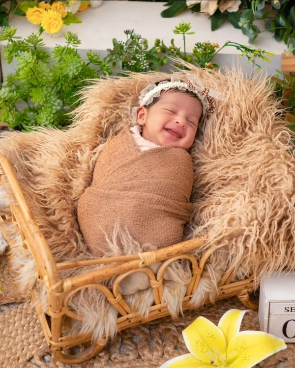 A newborn wrapped snugly in a brown swaddle smiles blissfully in their sleep. Capturing these fleeting dream-filled smiles is one of the most rewarding parts of a newborn session, a moment of pure, unscripted joy.