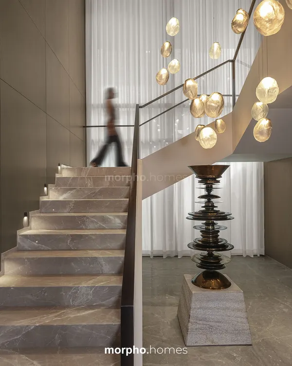 I conceived this staircase in a private residence as more than a vertical connector; it is a sculptural pause within the home. Clad in honed stone with integrated lighting, it rises alongside a cascade of pendant lights, transforming a functional element into an experience of light, material, and art.