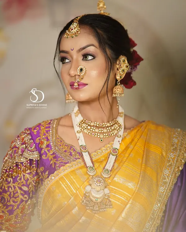 A classic Maharashtrian bridal portrait. The look features a beautiful yellow and purple Paithani saree, traditional jewelry including the Kolhapuri saaj, and makeup that highlights the bride's natural glow.