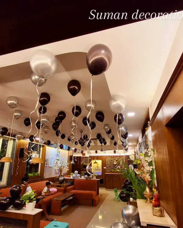 A view of a room decorated with black and silver helium balloons floating on the ceiling. This is an easy way to decorate a large space for a birthday or party.