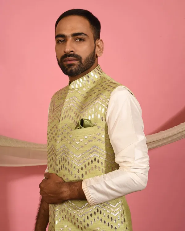 This pistachio green Nehru jacket is a fresh and modern choice for daytime events. The geometric foil work catches the light beautifully, and the matching pocket square adds a final touch of polish.