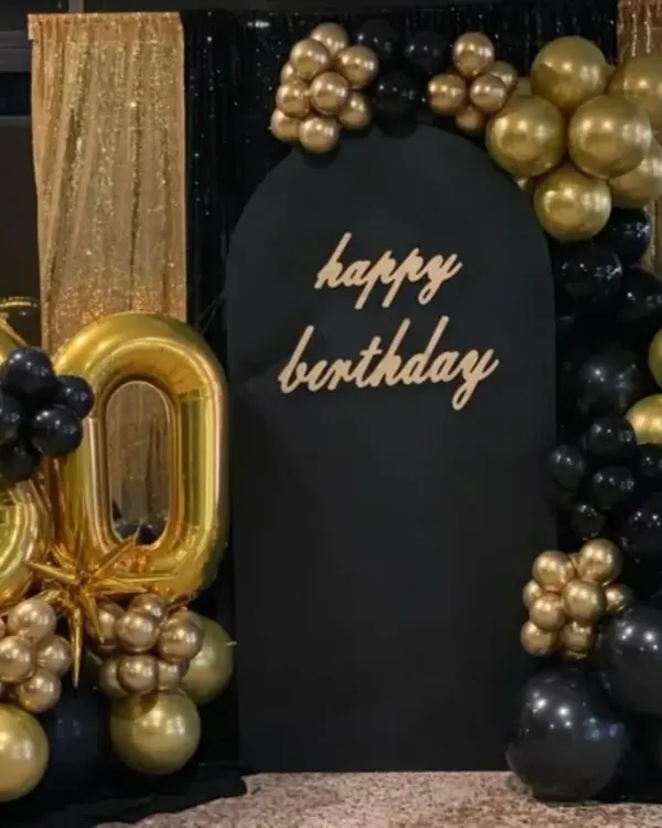 A stunning black and gold 30th birthday setup. This decor features a large foil number '30', a black arched backdrop, and a glamorous balloon arrangement against a gold sequin curtain.