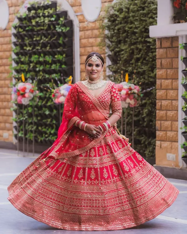 A full, twirling shot of this bride shows off her regal red lehenga. The makeup was designed to be timeless, with luminous skin and softly defined eyes that ensure she looks breathtaking from every angle.