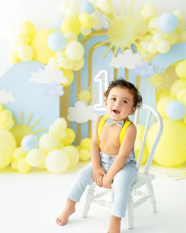 The pre cake calm! Dressed in an adorable bow tie and suspenders, this little man is all smiles in his sunshine themed first birthday setup, ready for the celebration to begin.