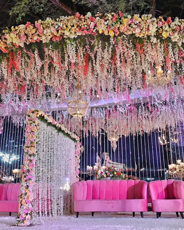 This reception stage is one of my signature designs, featuring a massive floral canopy with thousands of cascading flowers. The combination of pink and white florals with dramatic lighting creates a romantic, dream-like atmosphere for your big day.