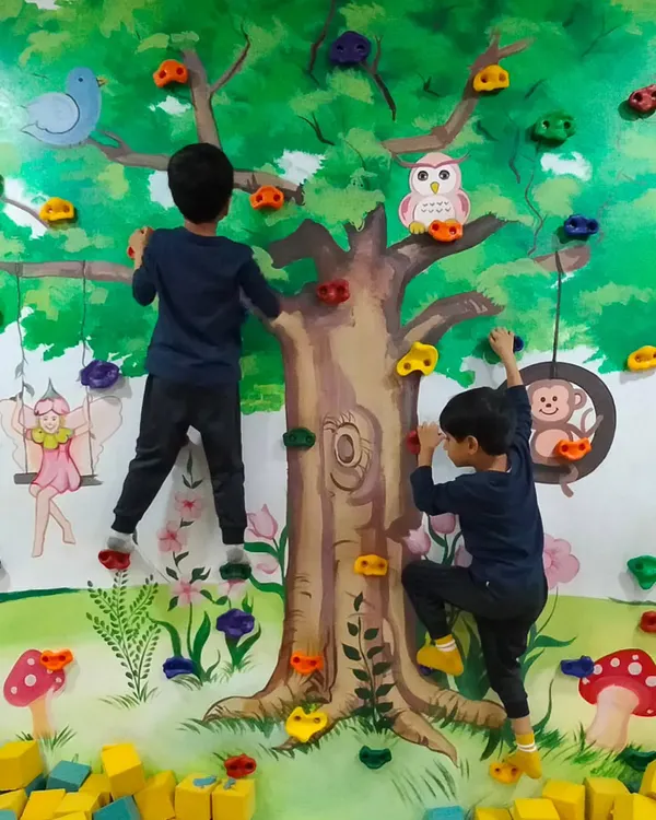 Two young ninjas work together to scale the tree-themed climbing wall. This activity is great for building strength, coordination, and confidence.