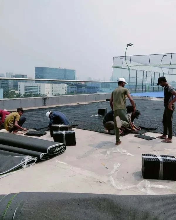 Our team installing modular drain mats on a large rooftop terrace. These mats, made from recycled polypropylene, create a crucial air gap for water to flow freely to drainage outlets.
