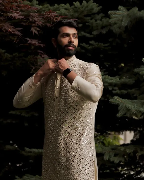 This ivory kurta set is a masterpiece of mirror work. The intricate hand embroidery covers the entire front of the kurta, creating a dazzling effect that is both traditional and incredibly stylish.