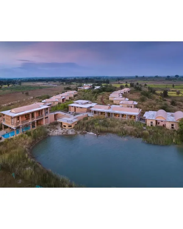 An aerial view of the Waghoba Ecolodge in Tadoba, Maharashtra, as dusk settles over the landscape. We designed this resort to blend seamlessly with the restored deciduous forest, creating a man-made lake that now enhances local biodiversity and offers tranquil views.