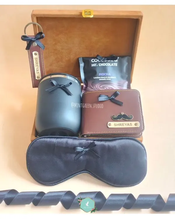 A classic and elegant gift hamper for him, perfect for a birthday or a dad-to-be. It features a personalized wallet and keychain, a travel flask, a luxurious sleep mask, and hot chocolate, all presented in a beautiful wooden box.
