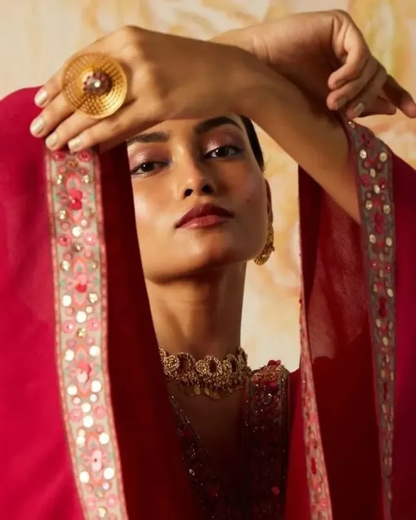 A close-up from a designer lookbook shoot, focusing on a soft yet impactful editorial makeup look. The blended pink eyeshadow and defined lip color complement the model's features without overpowering the intricate jewelry and garment details, making it perfect for fashion-forward campaigns.