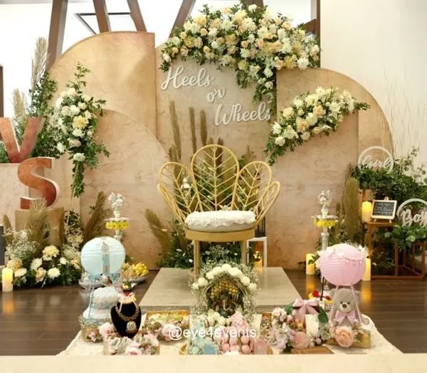 We designed this stunning "Heels or Wheels" gender reveal party with a chic, bohemian feel. The setup features natural textures, pampas grass, and elegant white and cream florals, all centered around a beautiful gold leaf-back chair for the mom-to-be. This theme creates a sophisticated and memorable way to share your big news.