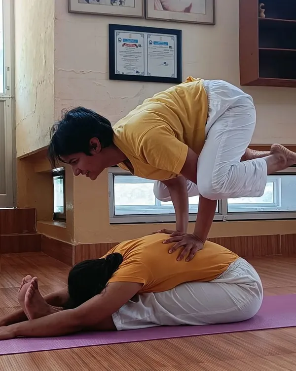 A moment of fun and connection at the Sivananda Ashram. Here, we are practicing a partner pose, combining a forward fold with an arm balance to build trust and strength.