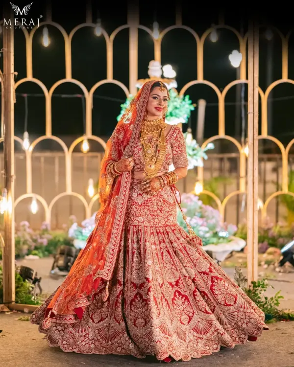 This is the quintessential bridal dream. A bride veiled in enduring majesty, shining in an eternal red lehenga, intricately detailed with hand embroidery that tells a story of heritage and opulence.