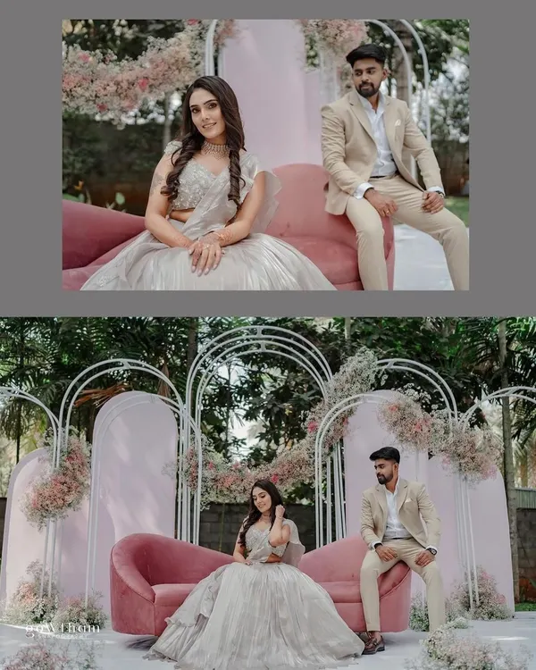 A closer look at the couple enjoying their beautifully styled engagement stage. The combination of the blush pink sofa and delicate floral arrangements on the white arches creates a soft, romantic setting.