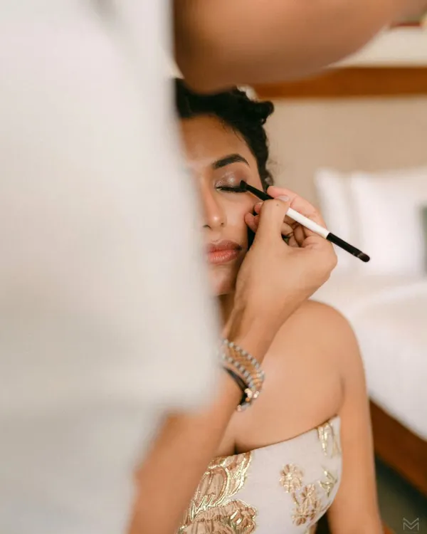 A close-up of a makeup artist applying eyeshadow to the bride. This shot captures the precision and artistry that goes into creating the perfect bridal look.