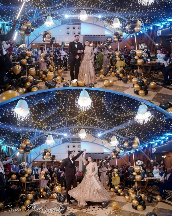 The couple makes a grand entrance at their engagement party, surrounded by balloons and fairy lights, ready to dance the night away.