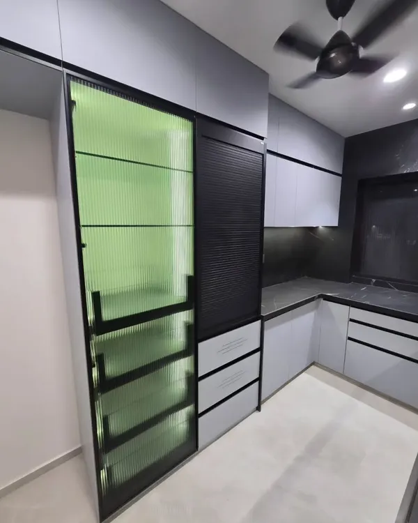 A close-up of our floor-to-ceiling pantry unit featuring a striking fluted green glass door. This detail adds texture, color, and a touch of retro elegance while partially obscuring the contents for a tidy look.