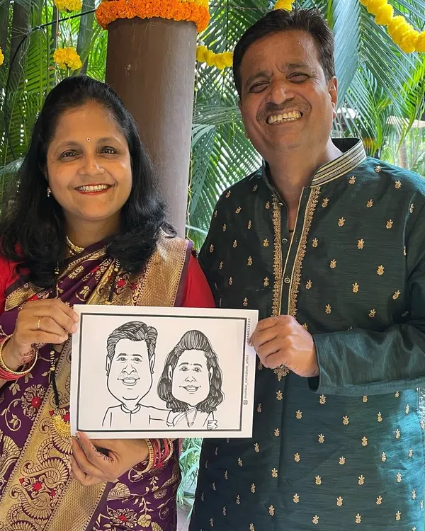 A happy couple holding their live caricature, drawn at a wedding function in Thane. It's a wonderful way to give guests a unique memento of your special day.