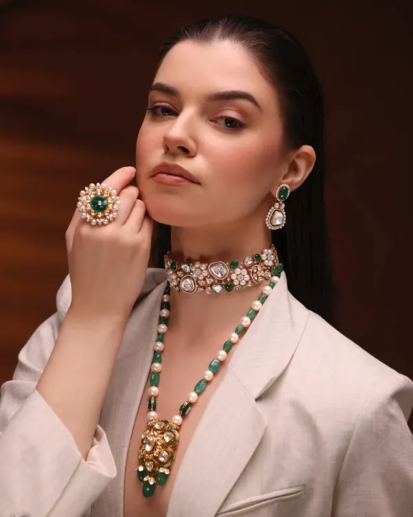 A powerful pose from a jewelry campaign. The makeup is clean and sculpted, with a strong brow and a neutral palette to ensure the focus remains on the exquisite emerald and polki jewelry.