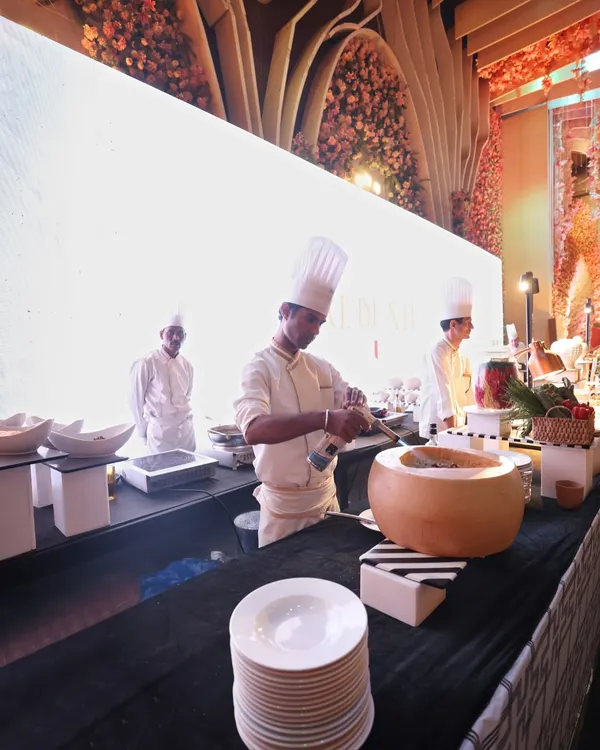 A chef at our live pasta station, tossing pasta in a hollowed-out wheel of Parmesan cheese. This is not just cooking; it's a performance that adds flavour and theatre to your event.