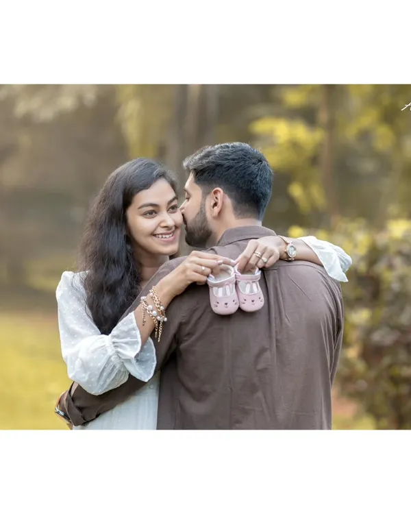 This is the moment it all becomes real. Here, the expecting mother shares a happy, knowing smile with her partner while holding up a tiny pair of baby shoes, a beautiful symbol of the little one they are eagerly awaiting.