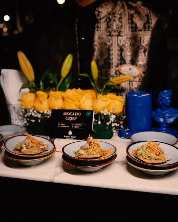A server presents our signature Avocado Crisps. This dish is a perfect example of my fusion approach, combining creamy avocado with a crunchy base for a delightful bite-sized appetizer.