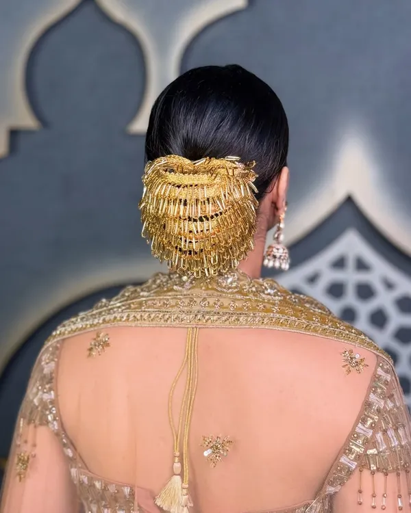A sleek, polished bun paired with a dramatic gold hair accessory creates a look of pure royalty. This is perfect for a bride wanting a statement reception hairstyle.