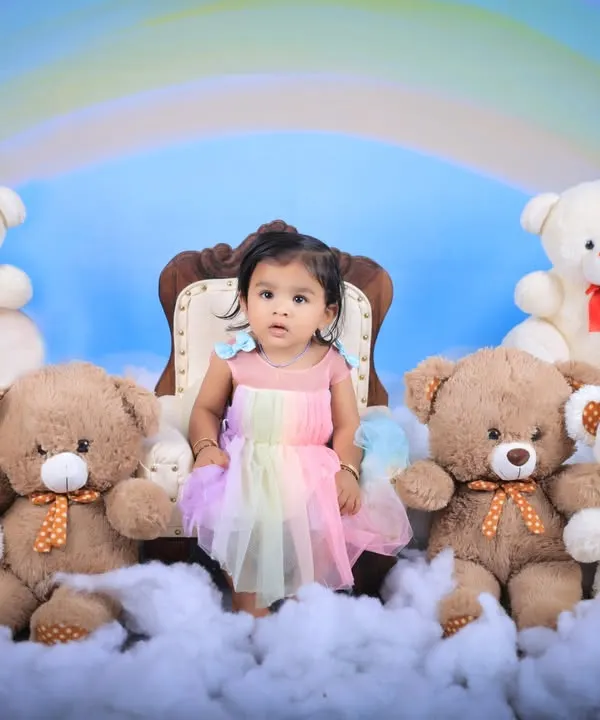 A dreamy rainbow and teddy bear picnic theme. This little girl in a pastel rainbow dress sits like a princess on her throne among the clouds and her furry friends.