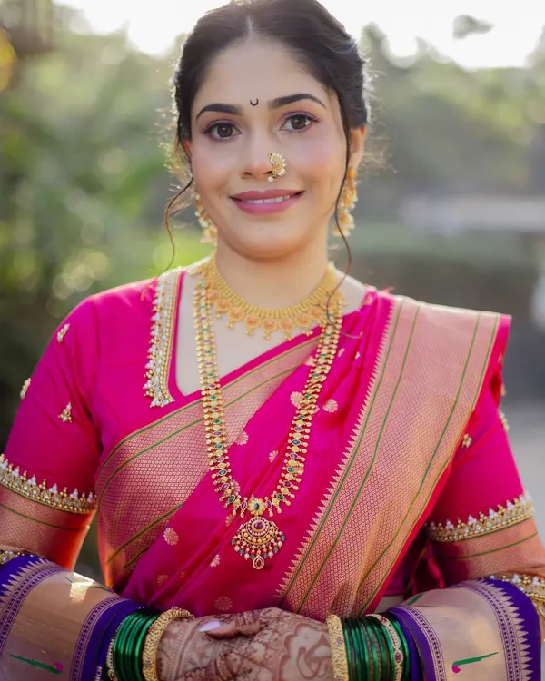 A full portrait of my beautiful bride in her pink Paithani Nauvari saree. The look features glowing skin, soft pink eyeshadow, and traditional gold jewelry, creating a perfect blend of modern grace and Marathi tradition.