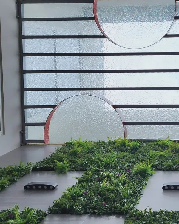 A view looking up from the courtyard in Dr. Harsha's home, showing the interplay of glass, greenery, and light.