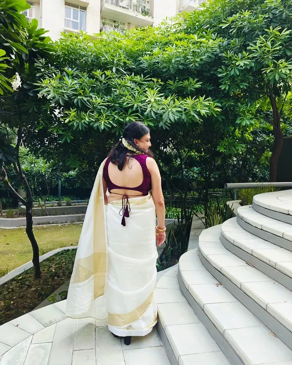 A closer look at the custom-stitched purple blouse. It features a deep back with a delicate tie-up, perfectly complementing the client's white and gold saree.