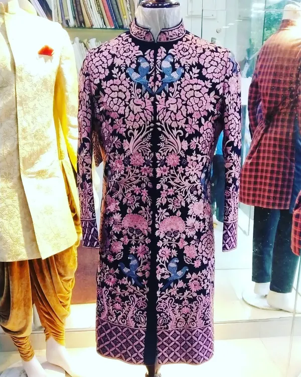 We specialize in creating one-of-a-kind groomswear that makes a statement. This black velvet sherwani, featuring intricate pink and blue floral embroidery, is a testament to our commitment to exclusive, luxurious design for your most important day.