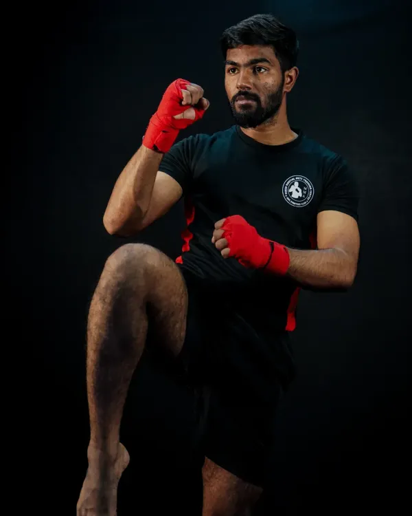 A fighter demonstrates a perfect knee strike, a fundamental and powerful weapon in Muay Thai and MMA. This studio shot highlights the form and balance required for effective striking.