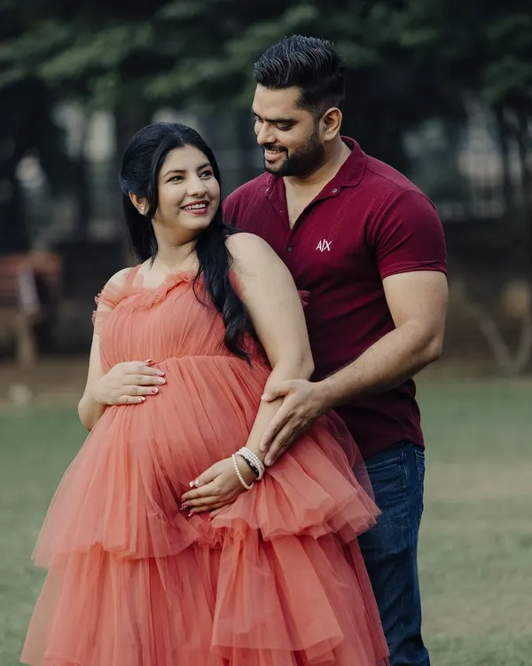 A beautiful maternity shoot moment. This couple looks so happy, and she is glowing in our peach-colored tiered tulle gown, which is a popular rental for photoshoots.