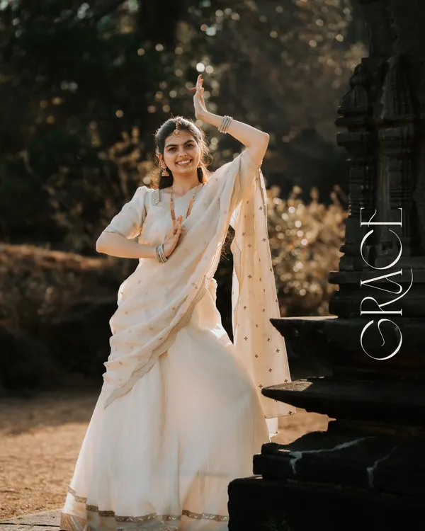 A portrait that captures the essence of grace. The bride-to-be's classical dance pose in a beautiful white lehenga against the backdrop of a traditional stone temple is pure poetry.