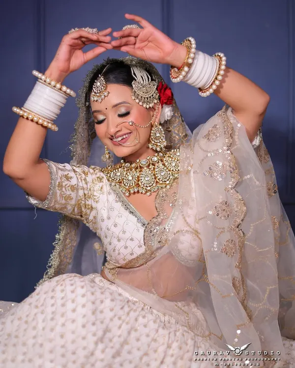 This is the dream bridal look. A complete, heavy Kundan jewellery set with a maang tikka, passa, nath, and layered necklaces, perfectly complementing an elegant white and gold lehenga. This shows the premium quality and attention to detail I offer for your big day.