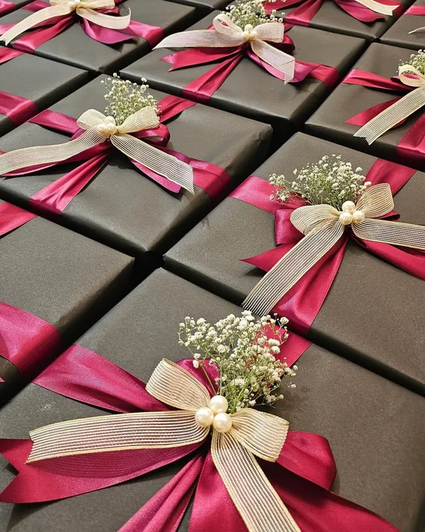 For a large corporate order for Shoppers Stop and Axis Bank, I wrapped each gift in dark paper and tied them with a combination of magenta satin and textured cream ribbons. A sprig of baby's breath and a few pearls add the perfect finishing touch.