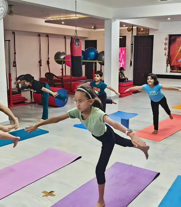 This is the heart of my kids' yoga class. Here, children learn to find their balance and focus, not by being perfect, but by enjoying the process together. We work on poses like this balancing stick pose to build strength and stability in a fun group setting.